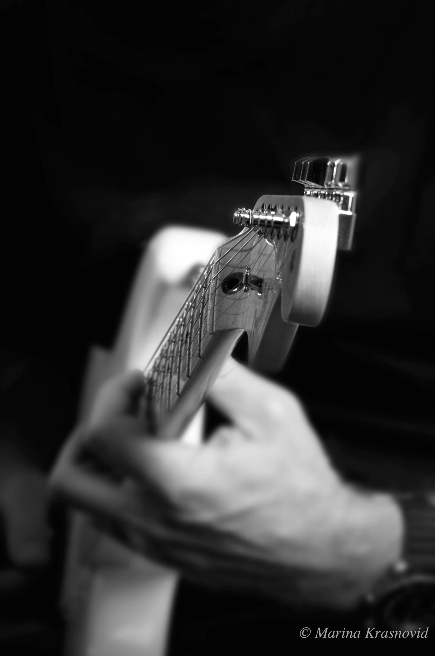 Close up of an electic guitar neck with human hands.