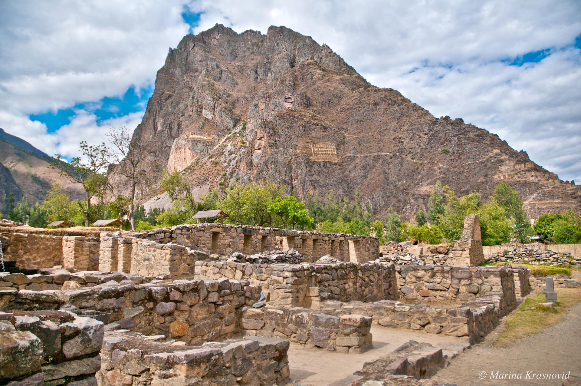 Ollantaytambo Ancient Inca fortress and archaeological site of Ollantaytambo, with massive stone terraces climbing the mountainside, stone walls of the citadel above, and a traditional town at the base of the Sacred Valley in Peru.