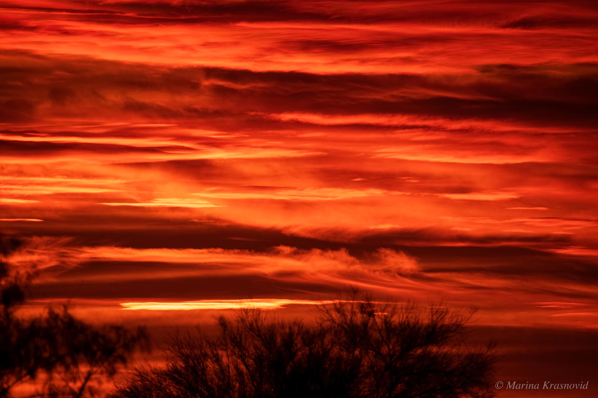 Fiery Arizona sunset with vivid red and orange clouds glowing above desert silhouettes | Photographed by Marina Krasnovid