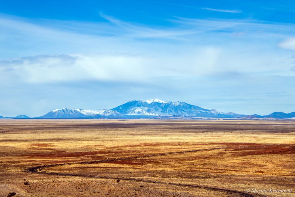 View from the rim of Meteor Crater across the high desert toward the snow-capped San Francisco Peaks in northern Arizona.